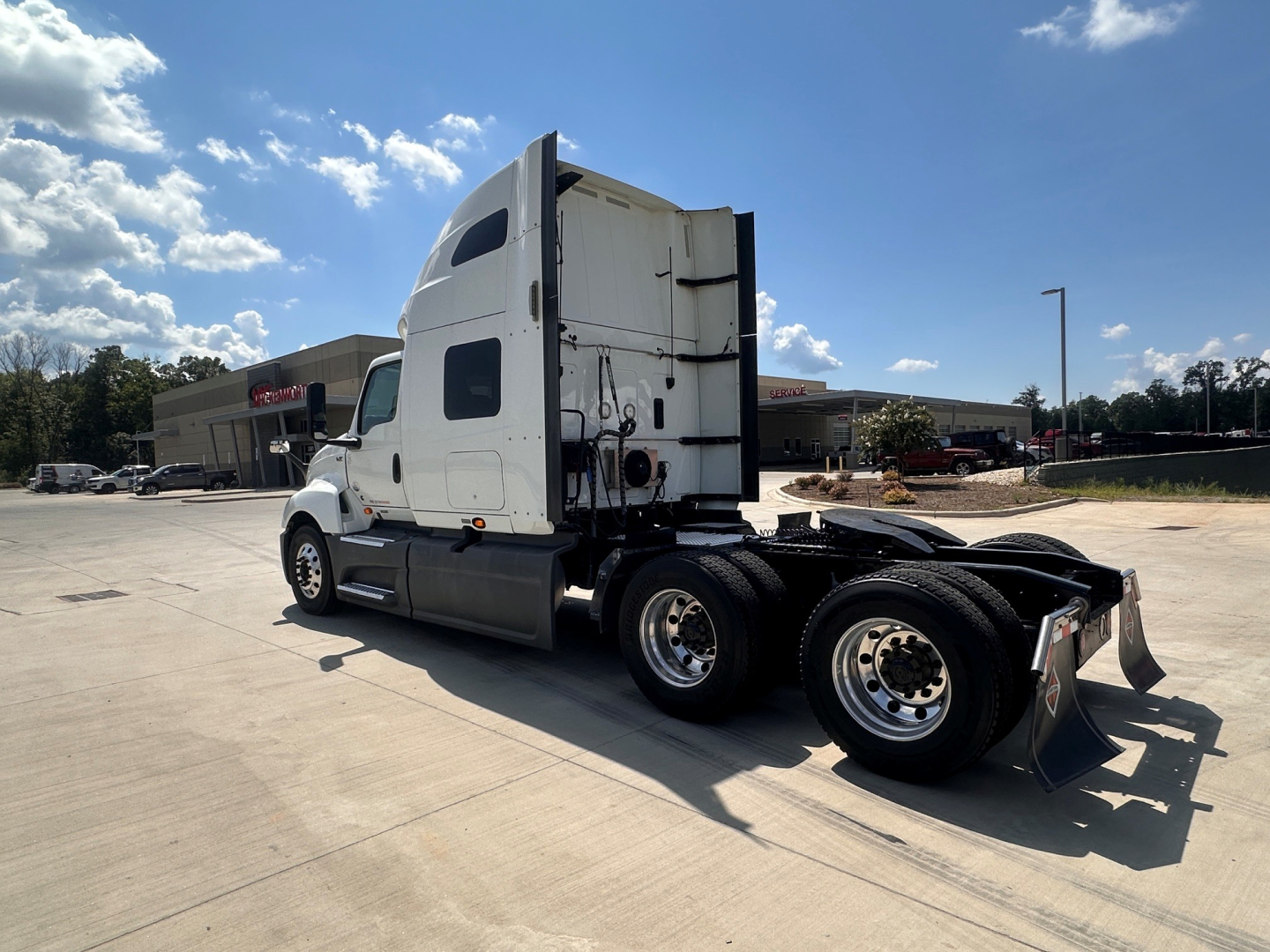 Truck cab of a white 2021 International LT625 tractor seen from the rear-left, with fifth wheel and dual rear axles in a parking lot.