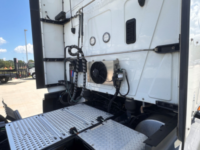 Truck cab rear showing A/C condenser fan and electrical lines on exterior panel of sleeper tractor