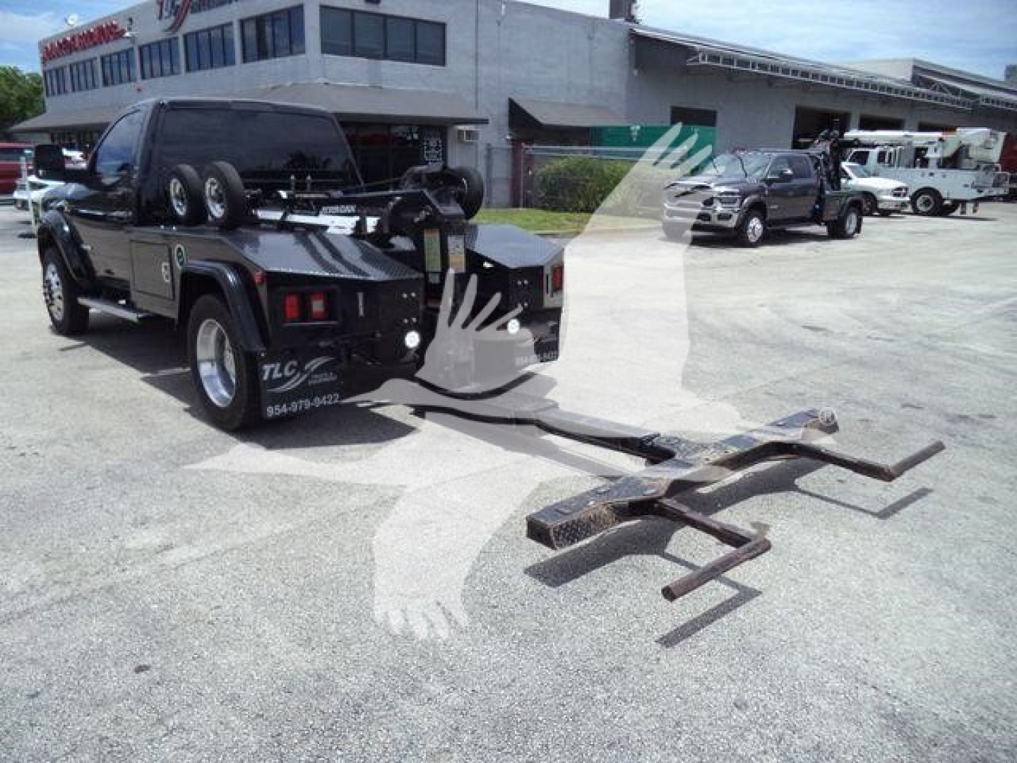 Ram 4500 tow truck with front-mounted winch and towing arms in an outdoor lot.