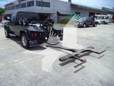 Ram 4500 tow truck with front-mounted winch and towing arms in an outdoor lot.