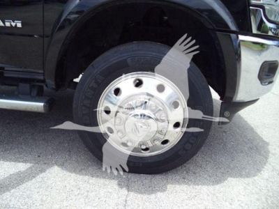 Truck wheel and tire on front left side of a RAM 2500/4500 series pickup with chrome hubcap and black fender; visible tire brand and wheel details partially obscured by watermark.