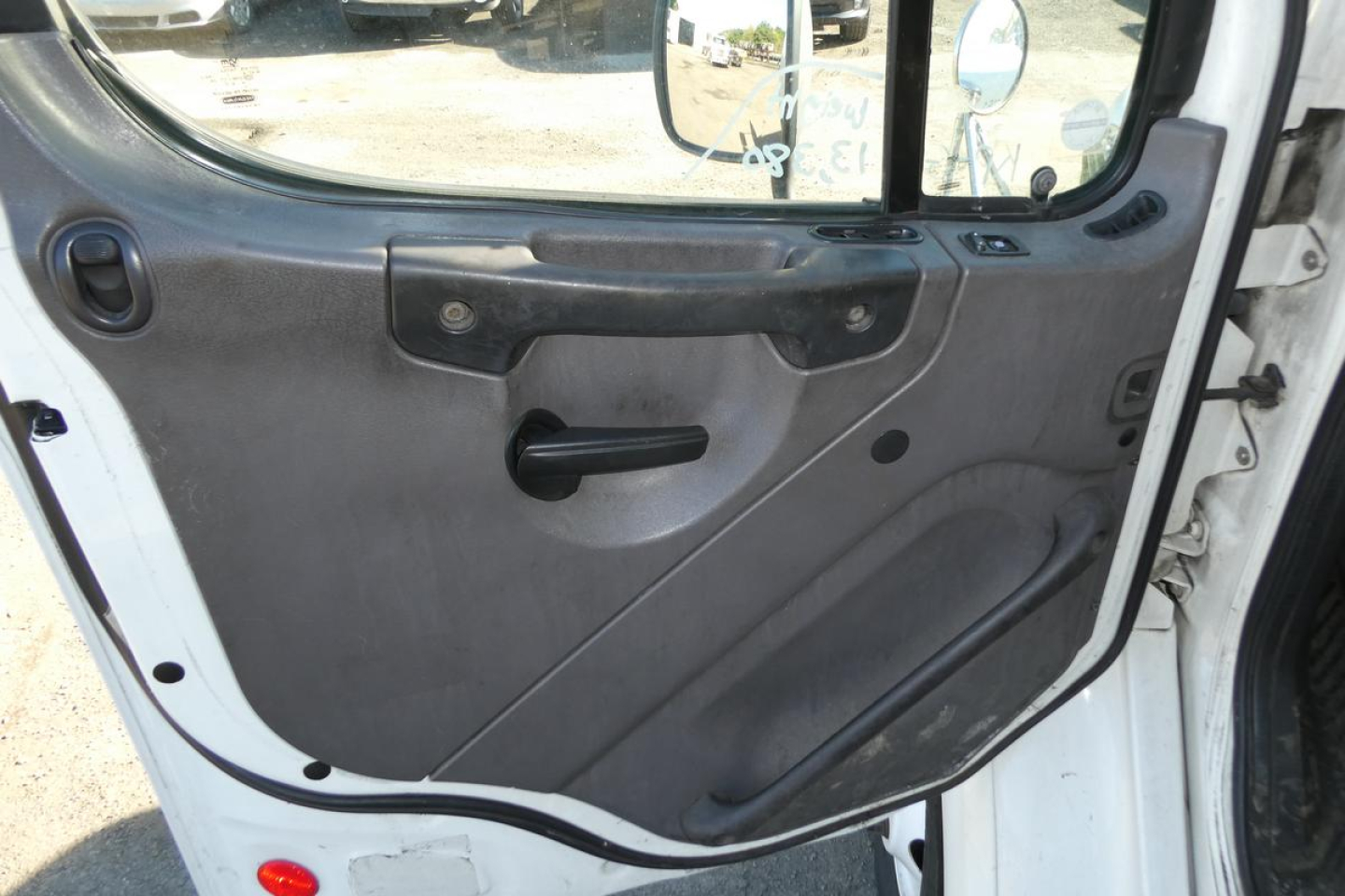 Truck cab interior door panel view showing window crank area and armrest on Freightliner M2 112 cab.