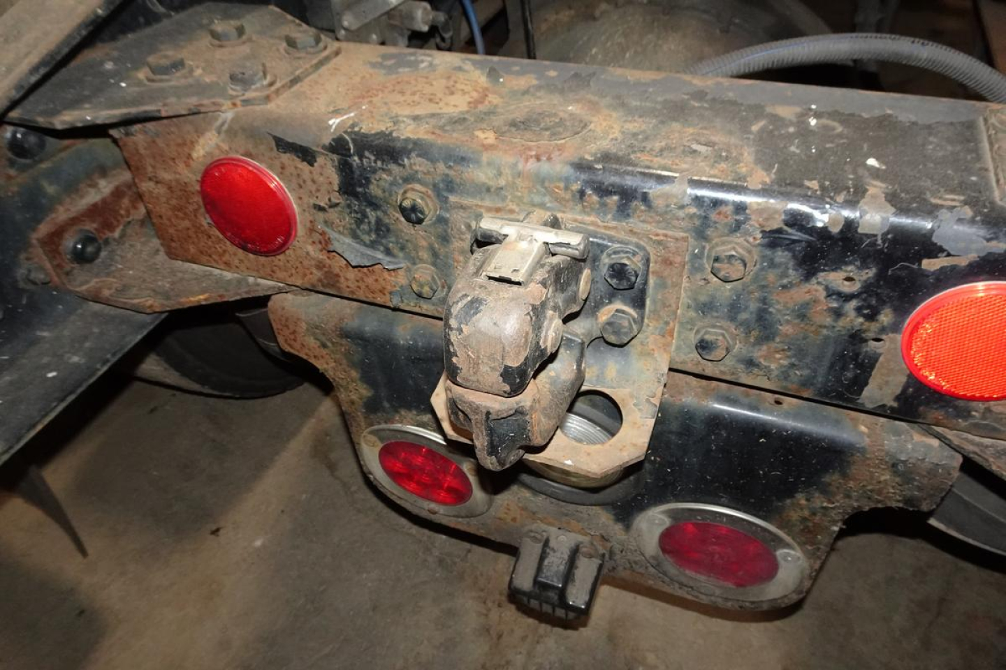 Rear of Freightliner M2 112 hitch area with connectors and circular red reflectors; dirty metal frame and wiring visible.