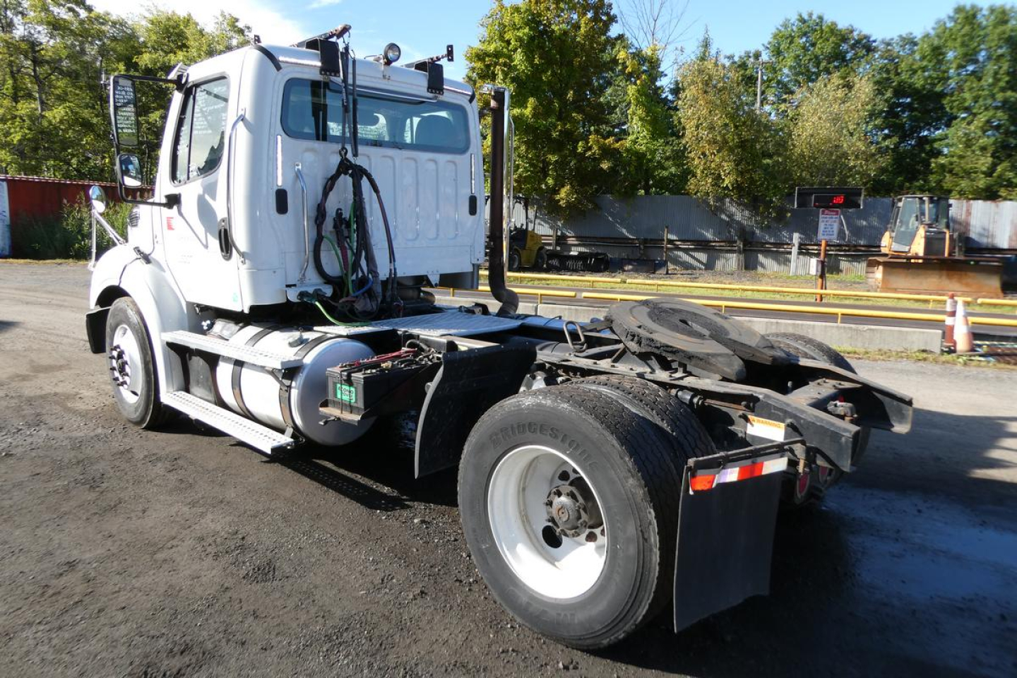 Truck chassis and cab of a Freightliner M2 112 medium-duty truck showing rear view with fifth wheel and fuel tank.