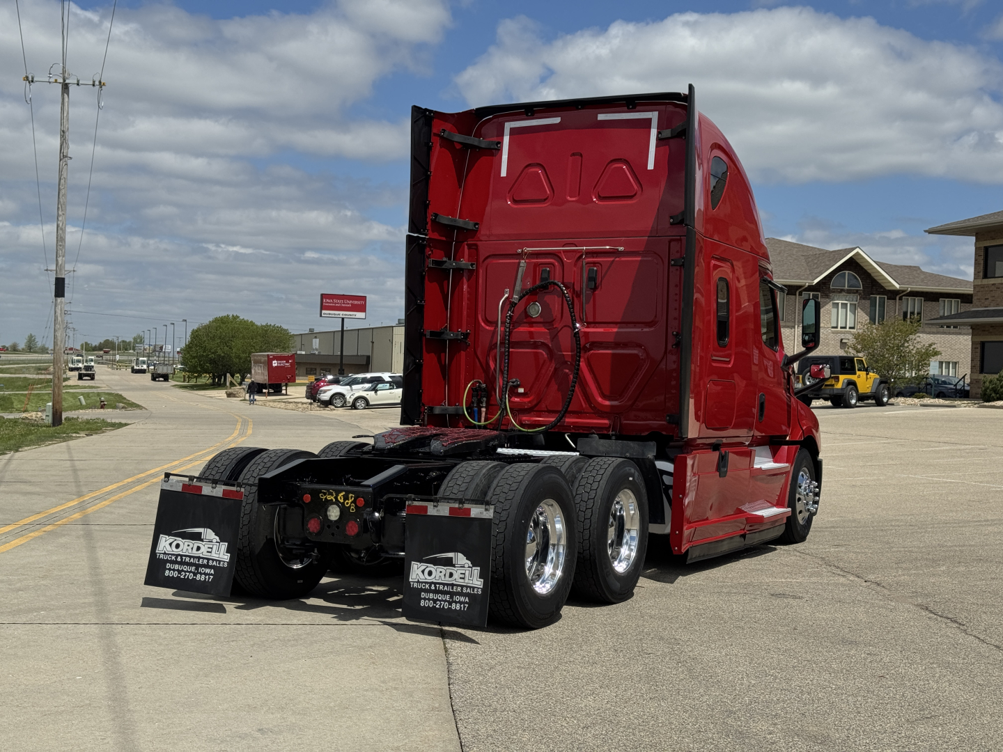 2019 Freightliner Cascadia 126 tractor trailer rear view showing rear wheels, red cab, and fuel/air lines; mudflaps readable