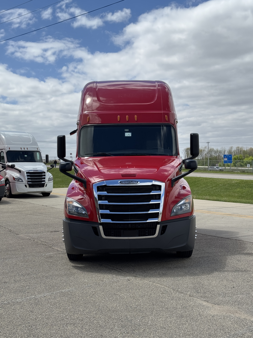 Front view of a red Freightliner Cascadia 126 sleeper tractor with chrome grille, large black bumper, and black mirrors.