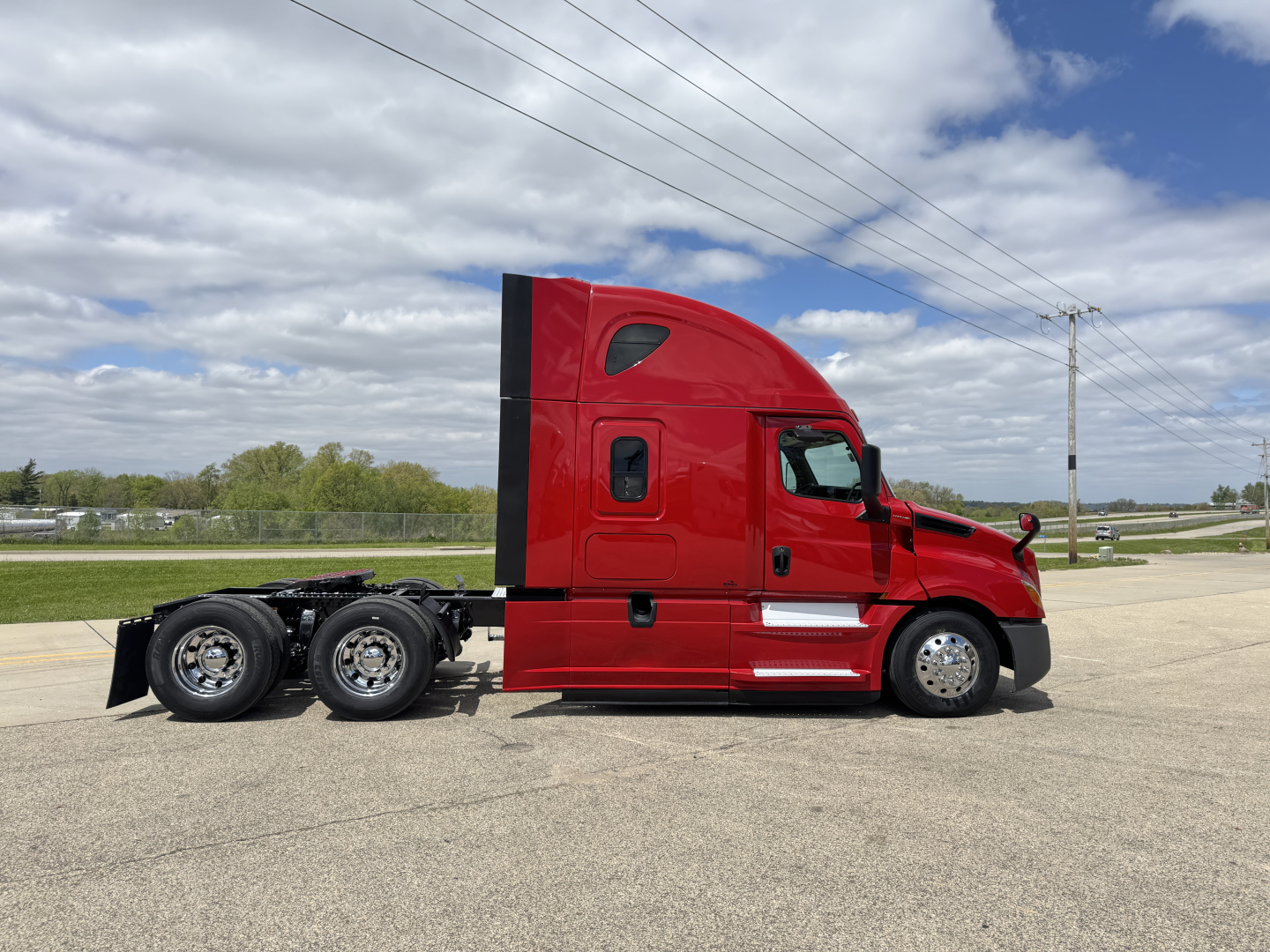 Truck side view showing a red 2019 Freightliner Cascadia 126 sleeper cab with three axles and a low-height chassis.