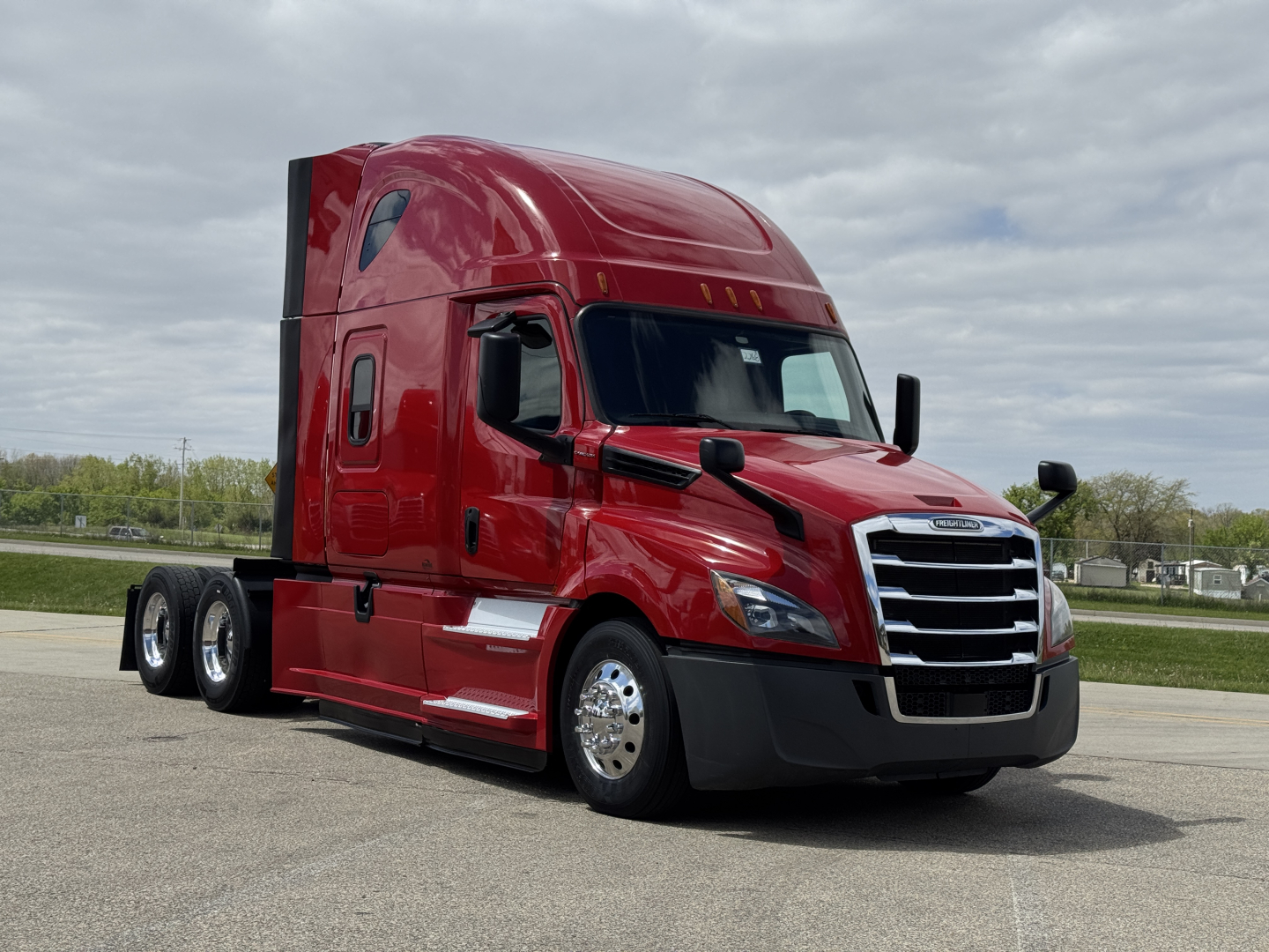 Red Freightliner Cascadia 126 semi-truck with sleeper cab, front grille, and dual rear axles visible.