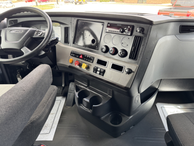 Cab interior of a 2019 Freightliner Cascadia 126 showing steering wheel, dashboard with gauges, center console, and cup holders.