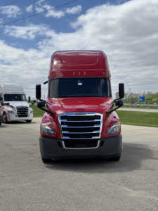 Front view of a red Freightliner Cascadia 126 sleeper tractor with chrome grille, large black bumper, and black mirrors.