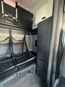 Freightliner Cascadia sleeper cab interior showing storage net, shelves, and cabin partition.