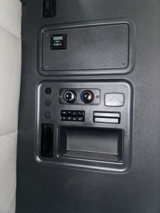 Cab interior panel of a 2019 Freightliner Cascadia showing a rectangular access panel, climate controls, and storage pocket in the dash area.