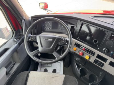 Truck cab interior of a 2019 Freightliner Cascadia showing steering wheel, instrument cluster, dashboard controls, and center console.