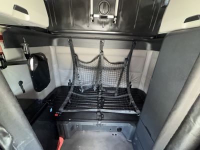 Freightliner Cascadia 126 cab interior showing cargo tie-down net and storage area with black metal rack.