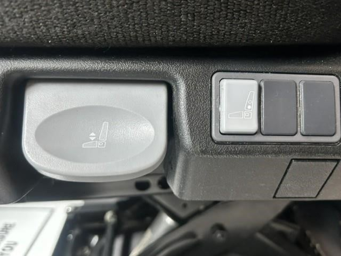 Cabin controls and seat adjustment lever in a Freightliner Cascadia 126 interior showing a circular knob and a row of buttons.