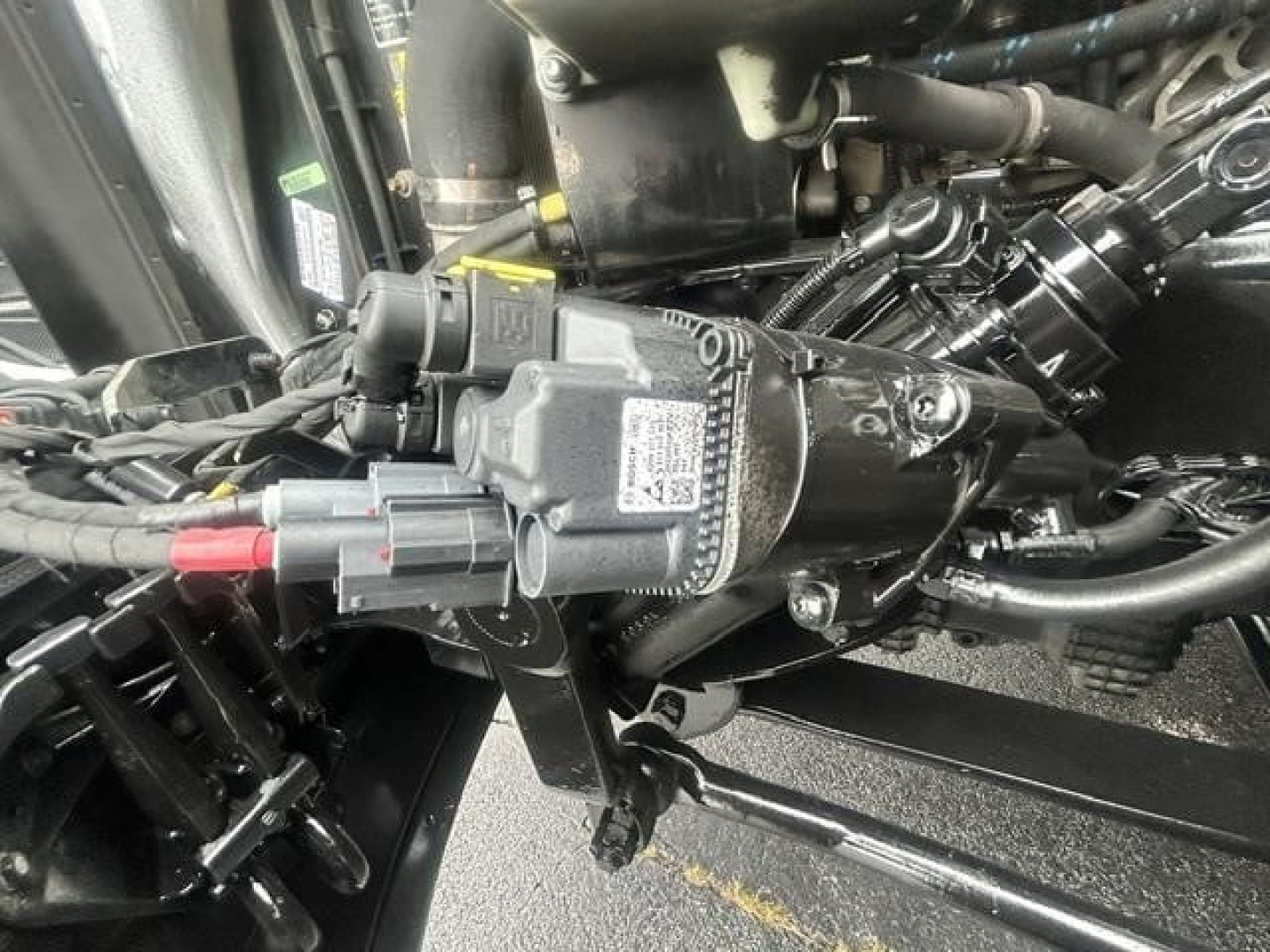 Engine bay showing auxiliary module with wiring harness and hoses in a Freightliner Cascadia cab chassis.