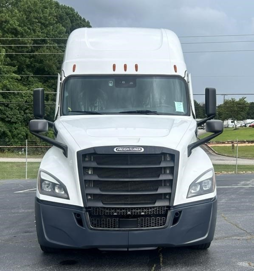 Truck front view of a white 2024 Freightliner Cascadia 126 sleeper with black grille and bumper, large side mirrors, and Freightliner emblem.