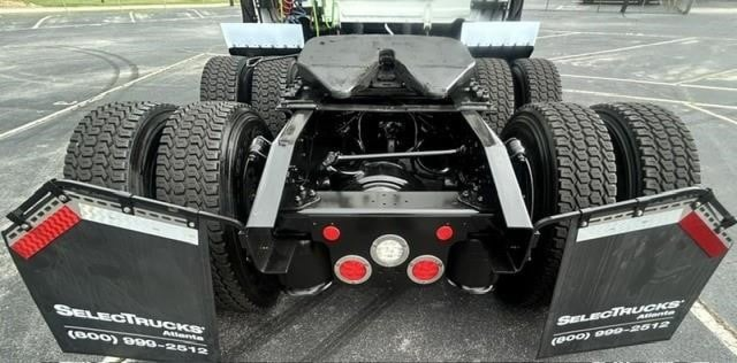 Truck rear view showing dual rear axles and fifth wheel on Freightliner Cascadia 126 chassis with mud flaps and dual tires.