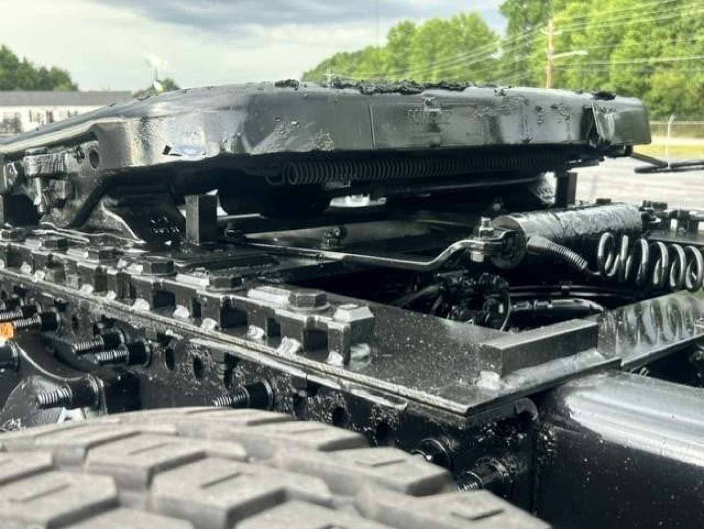 Freightliner Cascadia chassis showing suspension and frame components with hoses and coils visible under a damaged cab area.