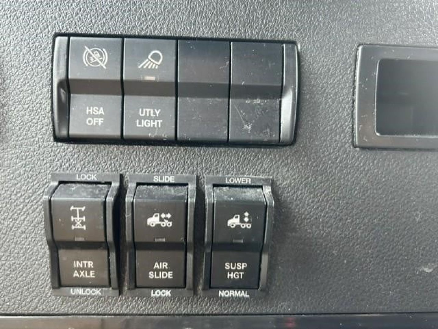 Freightliner Cascadia dash controls with HSA off, u t l y light, and various vertical toggles for lock, slide, air slide, susp height.