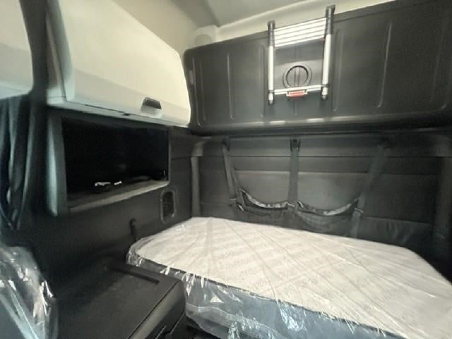 Freightliner Cascadia sleeper cab interior with bed and storage compartments visible.