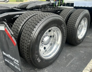 Truck dual rear axles with Michelin tires on polished rims, Freightliner Cascadia 126 chassis, wheel well and mudflap visible.