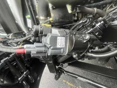 Engine bay showing auxiliary module with wiring harness and hoses in a Freightliner Cascadia cab chassis.