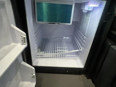 Fridge/freezer compartment of a Freightliner Cascadia 126 cab interior showing empty stainless steel shelving and control panel.