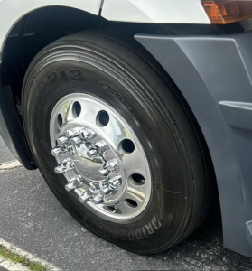 Truck front wheel assembly showing radial tire with steel wheel and chrome hub, Freightliner Cascadia 126 side view.