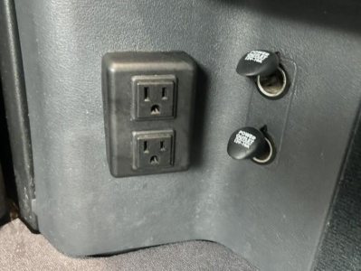 Two electrical outlets panel and two round 12V power ports labeled 'POWER TECH' on Freightliner Cascadia 126 interior side wall.