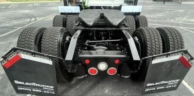 Truck rear view showing dual rear axles and fifth wheel on Freightliner Cascadia 126 chassis with mud flaps and dual tires.