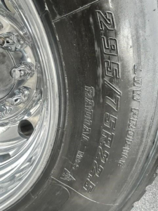 Tire sidewall showing 295/75R22.5 and Ultra-High Pressure tire details on a Freightliner Cascadia wheel.