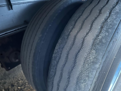 Tire close-up on Conestoga trailer wheel with wear lines visible.