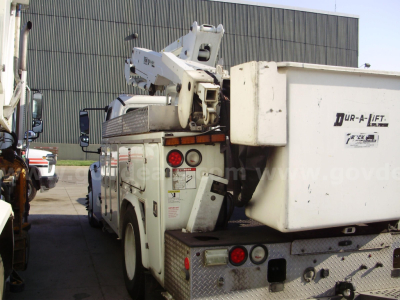 Freightliner M2 106 bucket truck with boom lift and utility bed, side view showing rear compartments and hydraulic lift.