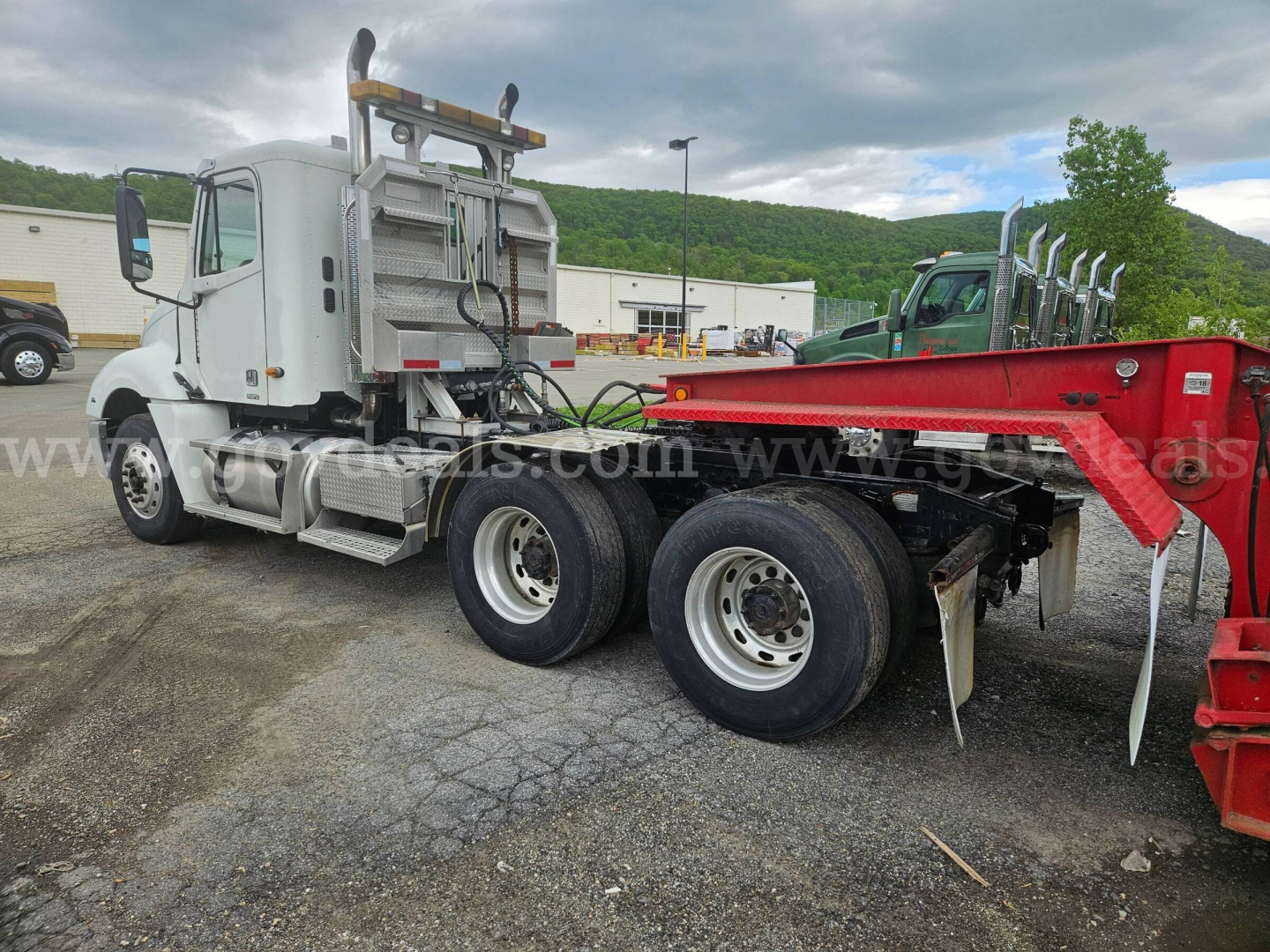 Truck side view showing Freightliner Columbia 120 tractor with attached red trailer/arm component and dual rear axles.