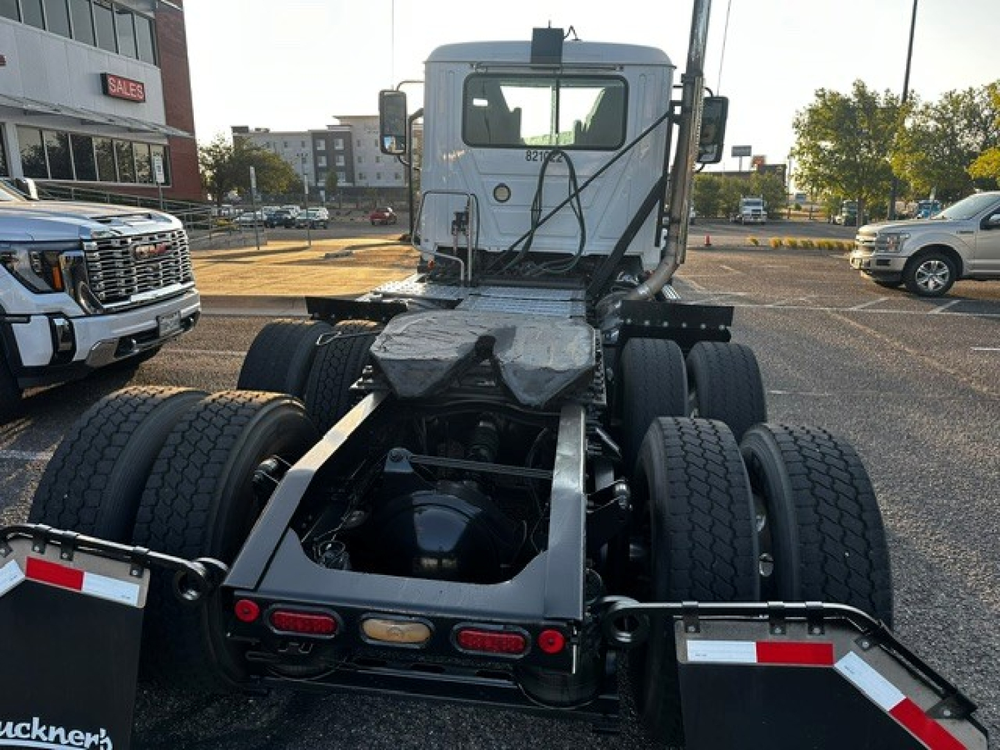Truck chassis view showing rear dual rear axles, fifth wheel area, and back of cab. Visible are dual rear tires on both sides, frame rails, fifth wheel mounting, and rear lights.