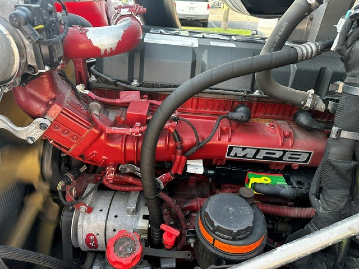 Engine bay of a 2021 Mack Anthem showing red engine components, belts, hoses, and a black top cover with MB3 label.