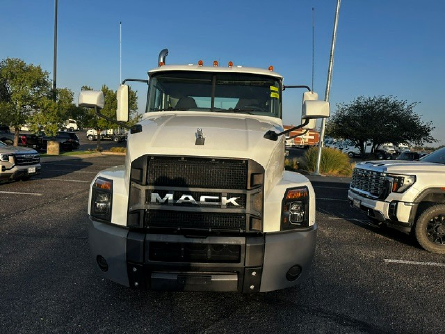 Front view of a white 2021 Mack Anthem daycab truck with large grille and bumper, headlight clusters, and side mirrors.