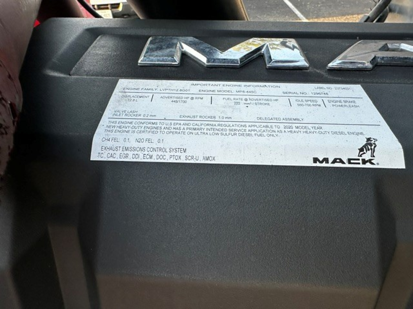 Mack engine bay label showing important engine information plate on black cover.