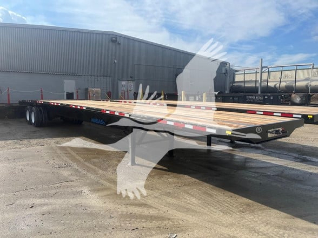 Flatbed trailer in lot showing long wooden deck planks and dual axle rear, black frame, reflective safety tape along sides.