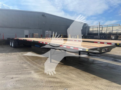 Flatbed trailer in lot showing long wooden deck planks and dual axle rear, black frame, reflective safety tape along sides.