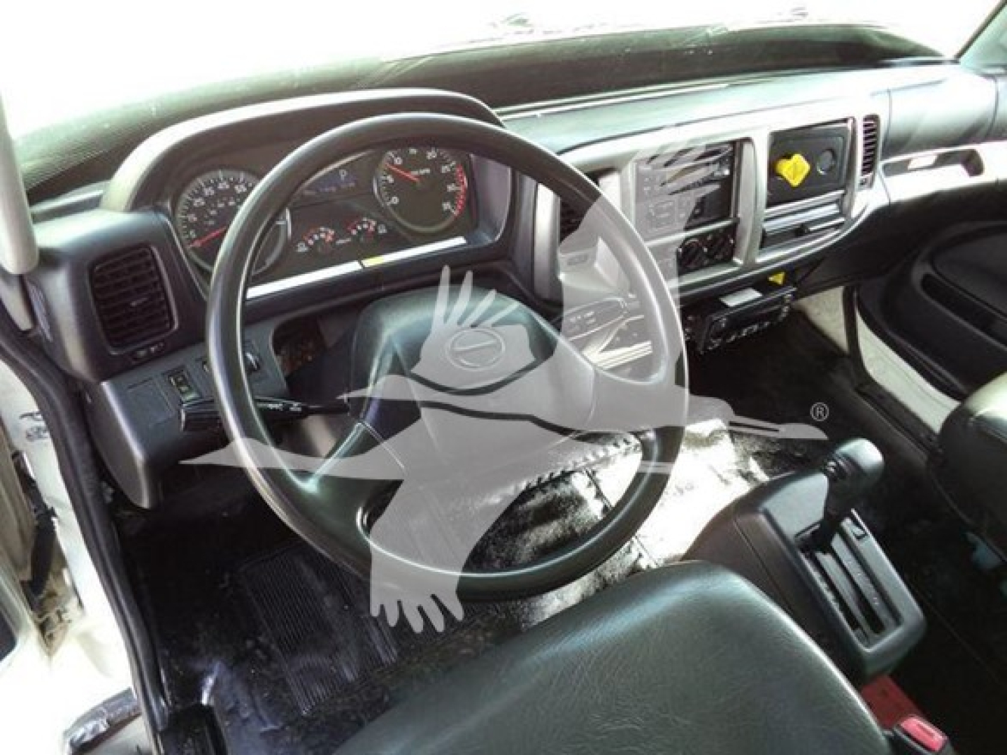 Dashboard and steering wheel of a 2015 Hino 268A truck cab interior showing steering wheel, instrument cluster, center console, and gear selector.