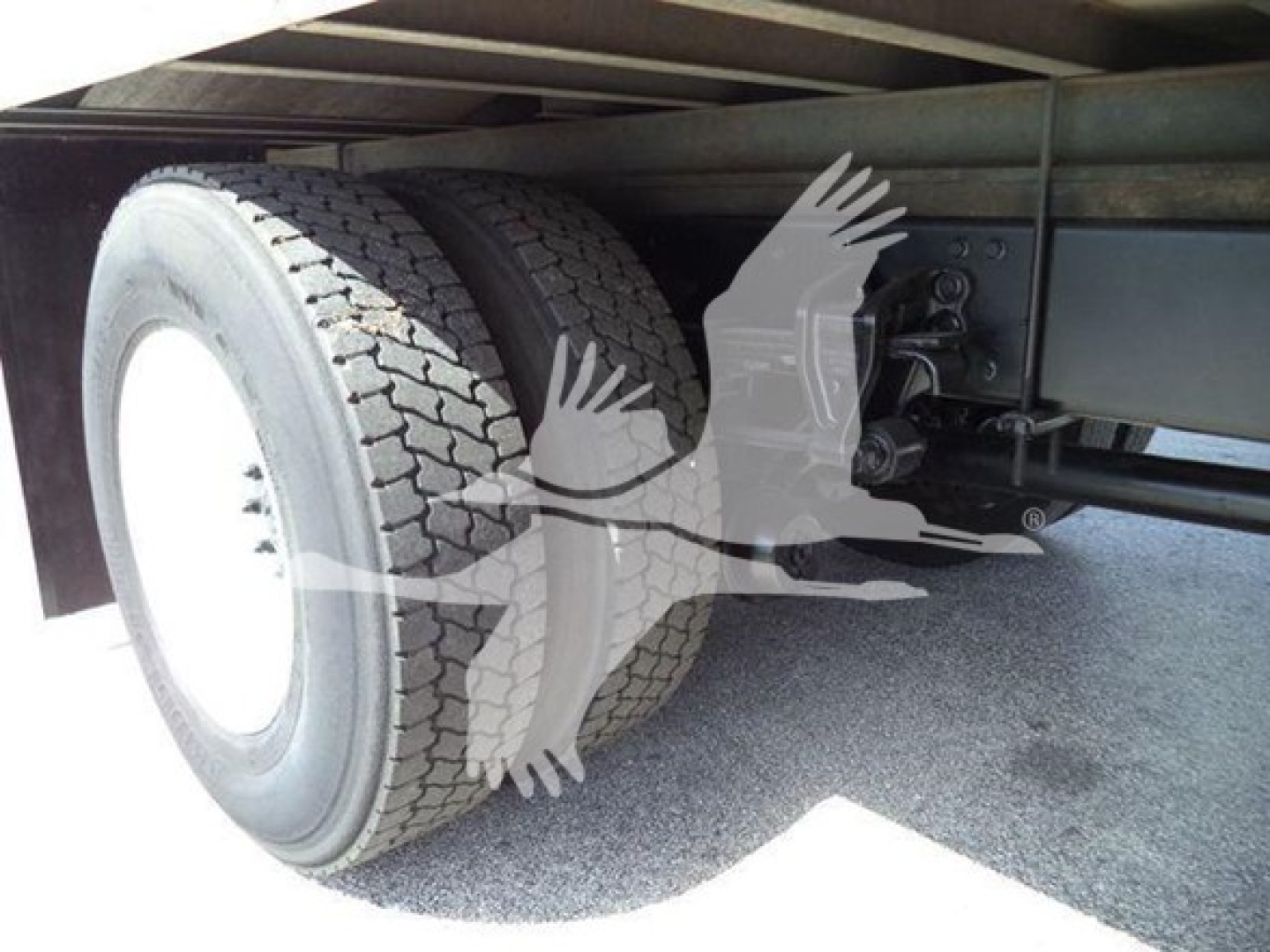 Refrigerated truck rear axle showing dual rear tires and undercarriage components.