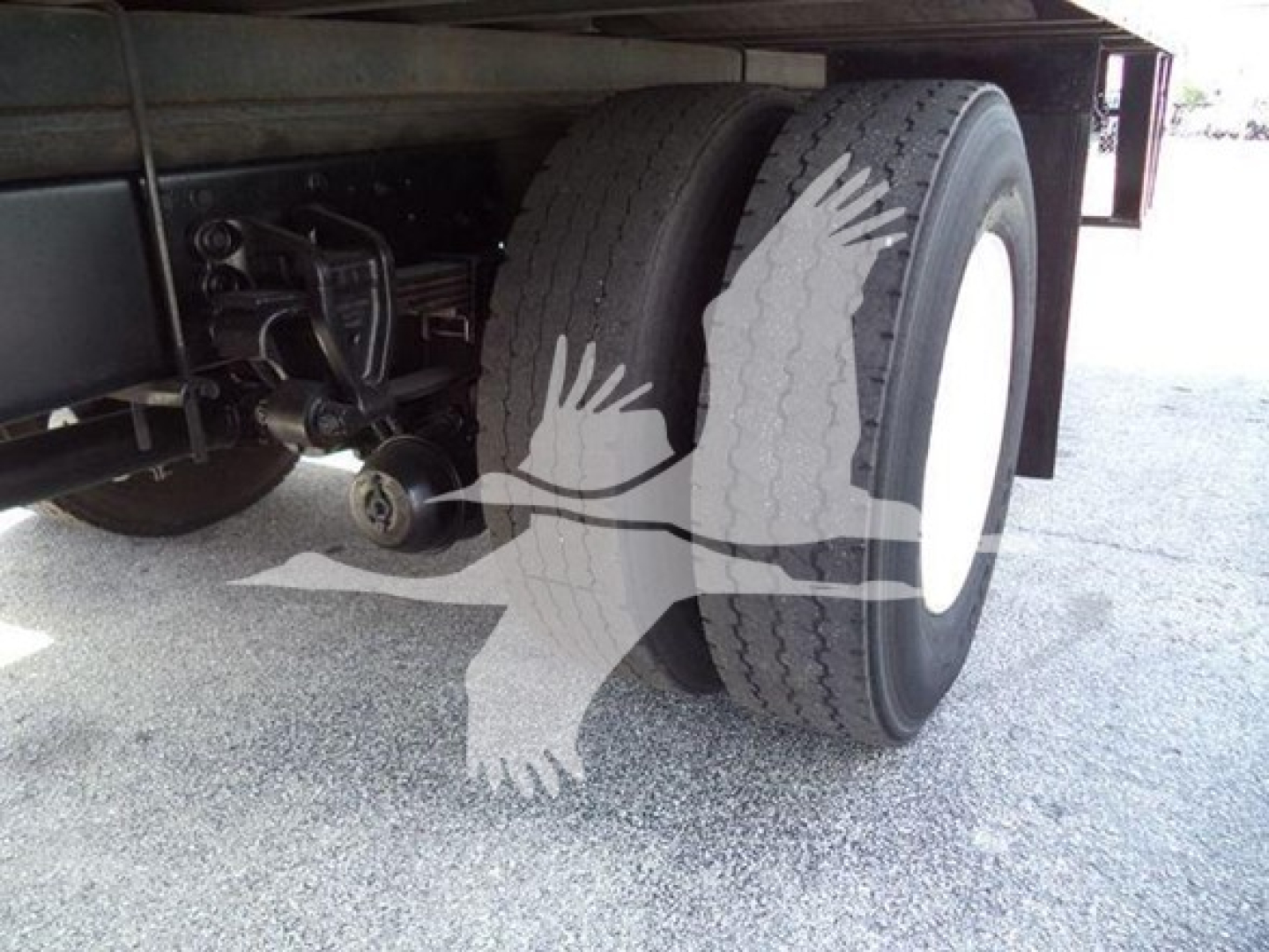 Refrigerated truck rear dual wheels and undercarriage showing tire tread and suspension components.