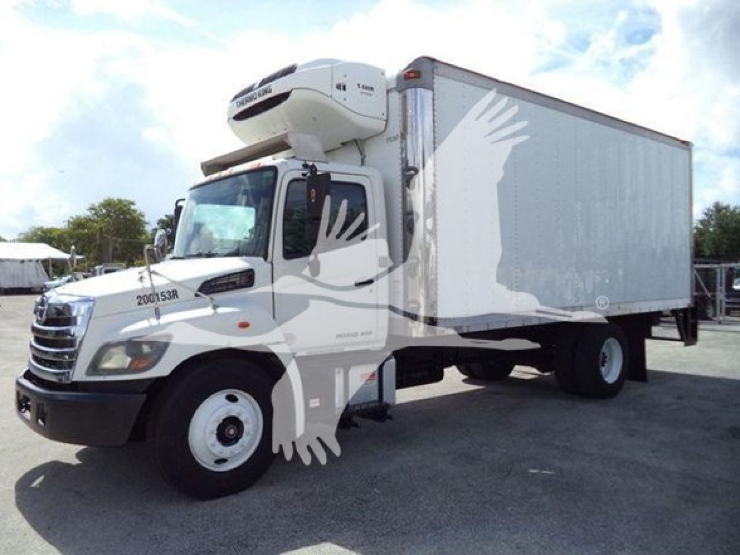 Truck in-service 2015 Hino 268A refrigerated box truck with freezer unit on cab roof and side-and-rear advertisements, front three-quarter view.