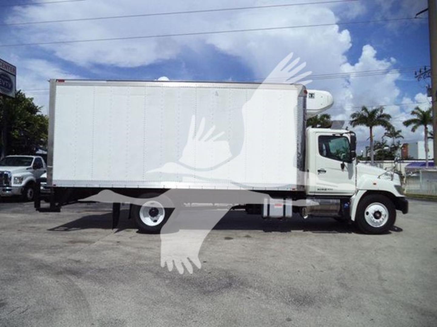 Truck in side view showing a white refrigerated box on chassis, Hino 268A model, medium-duty truck.