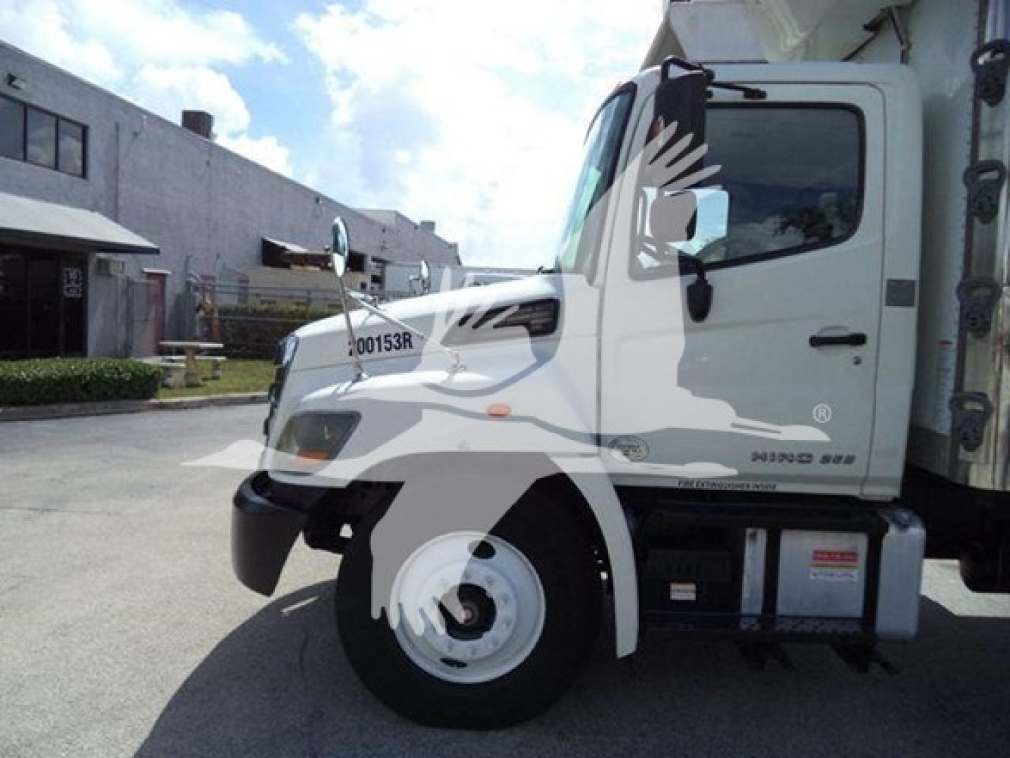 Truck cab of a 2015 Hino 268A refrigerated truck showing side view with white cab and engine bay area, VIN tag, and stock number visible.