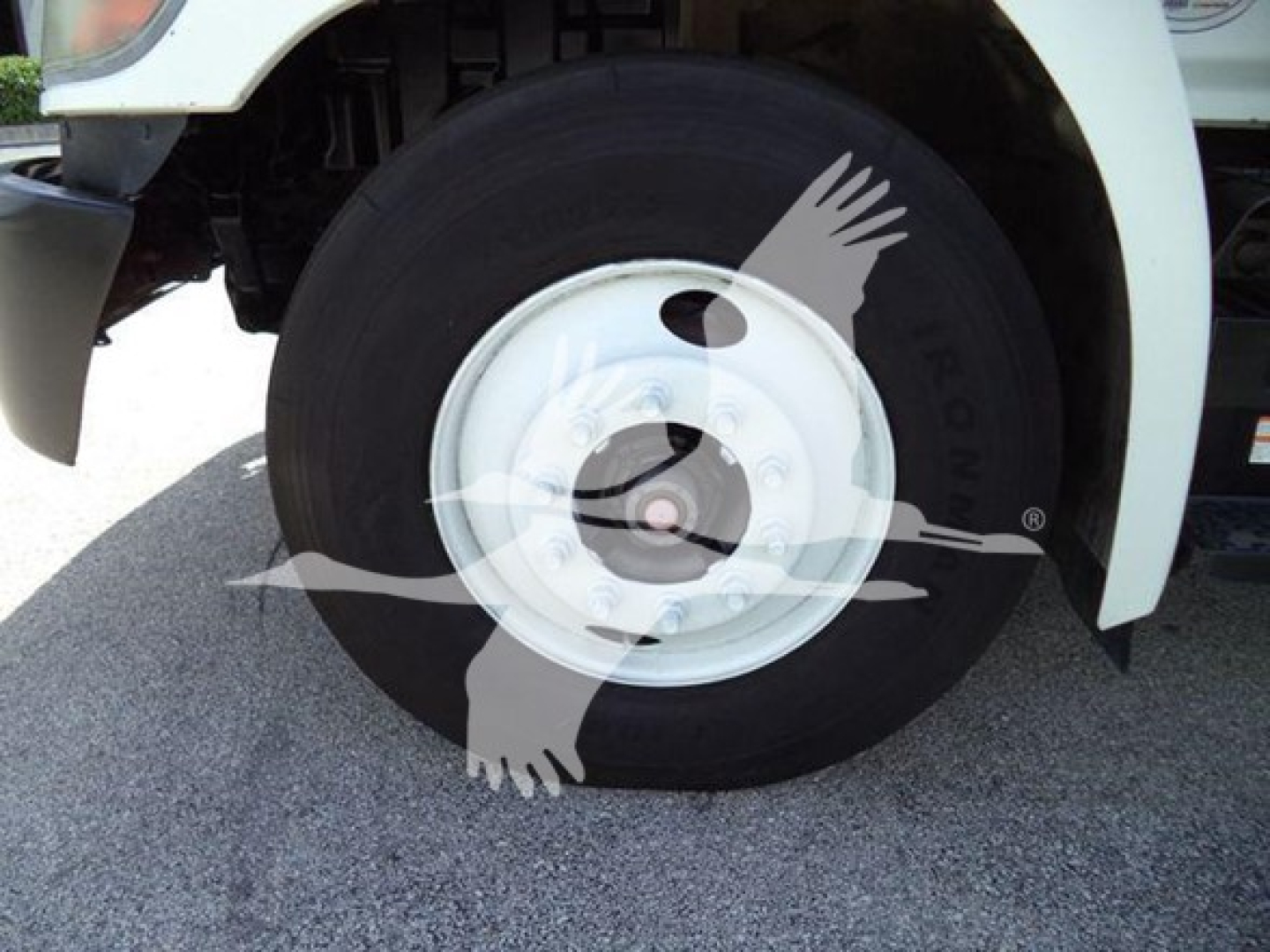 Front wheel of a 2015 Hino 268A refrigerated truck with white wheel hub and black tire; partial front fender visible.