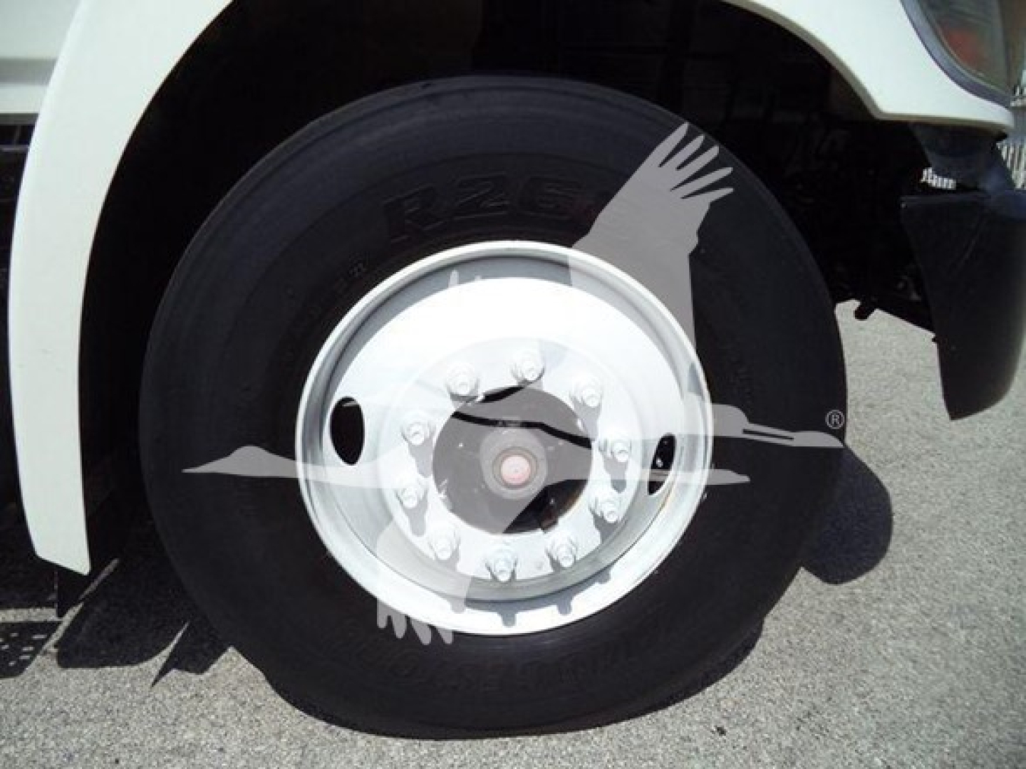 Truck front wheel of a 2015 Hino 268A in-service with white rim and black tire showing hub and fender