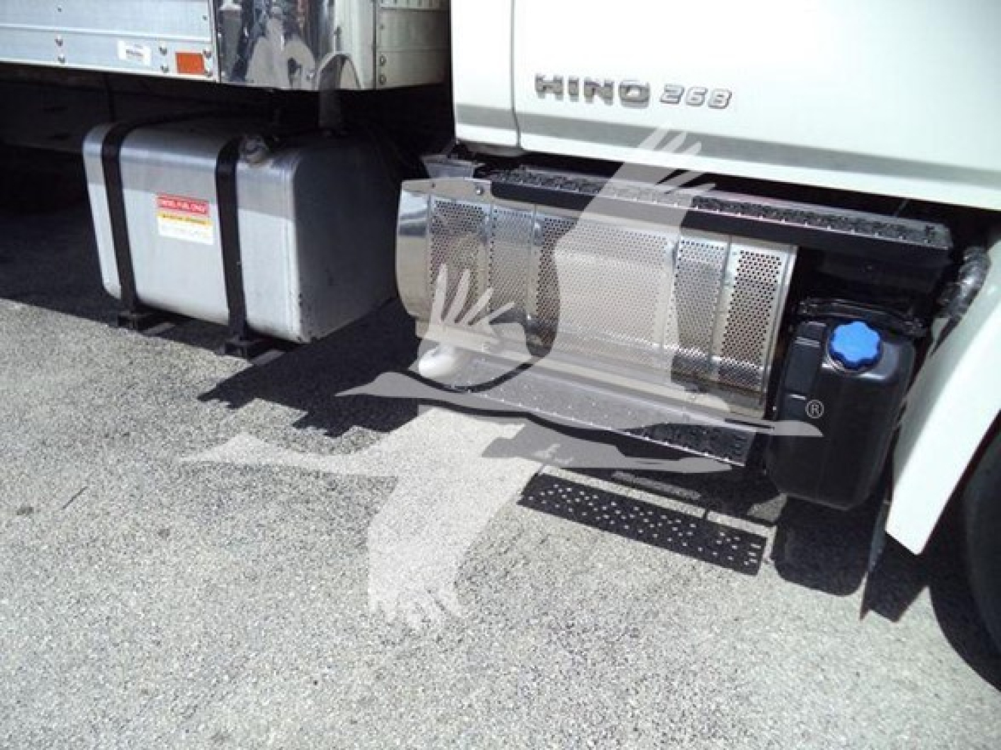 Hino 268A truck side showing fuel tanks and side steps with metal mesh guard and blue cap; visible HINO badge on cab; refrigeration truck category.